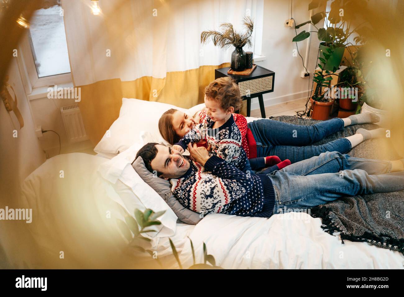 Bonne famille mère, père et garçon ont un plaisir sur le lit à la maison.Chandails de Noël.Vue de dessus. Banque D'Images