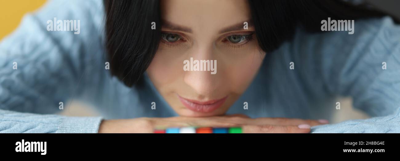 Une femme triste fatiguée regarde le cube de Rubik non collecté Banque D'Images