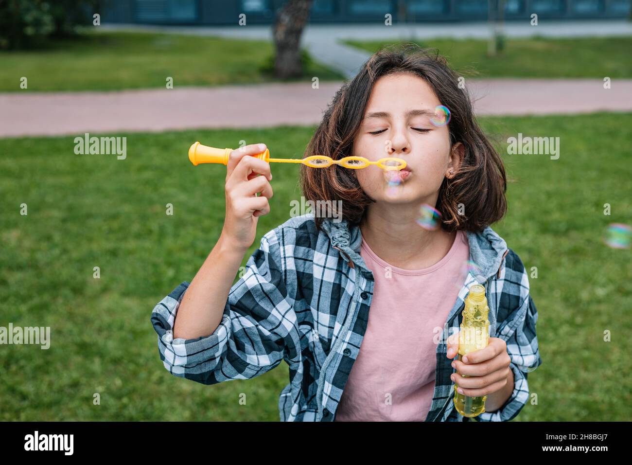 Une jeune fille d'origine caucasienne attirante fait des bulles de savon.Portrait d'une jolie fille brune s'amusant dans un parc d'été.Emot positif Banque D'Images