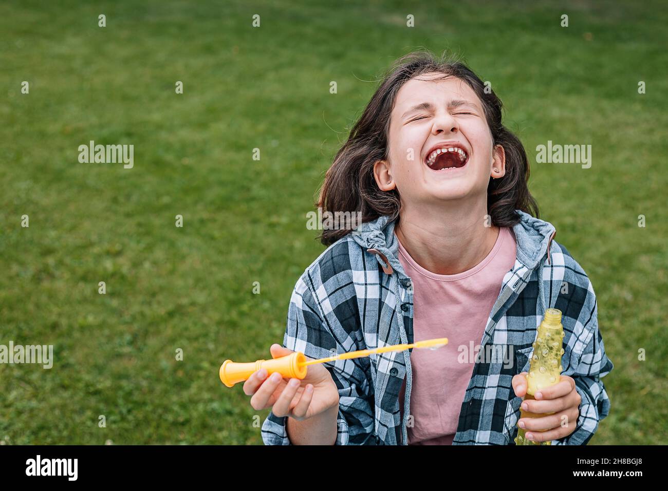Portrait d'une jolie fille brune s'amusant dans un parc d'été.Rire de l'école de race blanche avec des bulles de savon.Bonne enfance.Po Banque D'Images