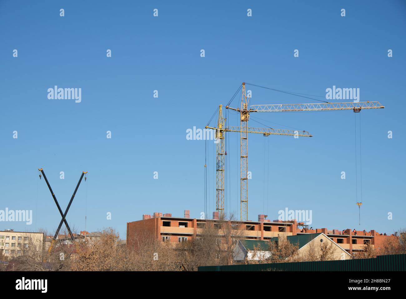 Deux grues à hauteur élevée et deux petites grues sont impliquées dans la construction de bâtiments résidentiels. Banque D'Images
