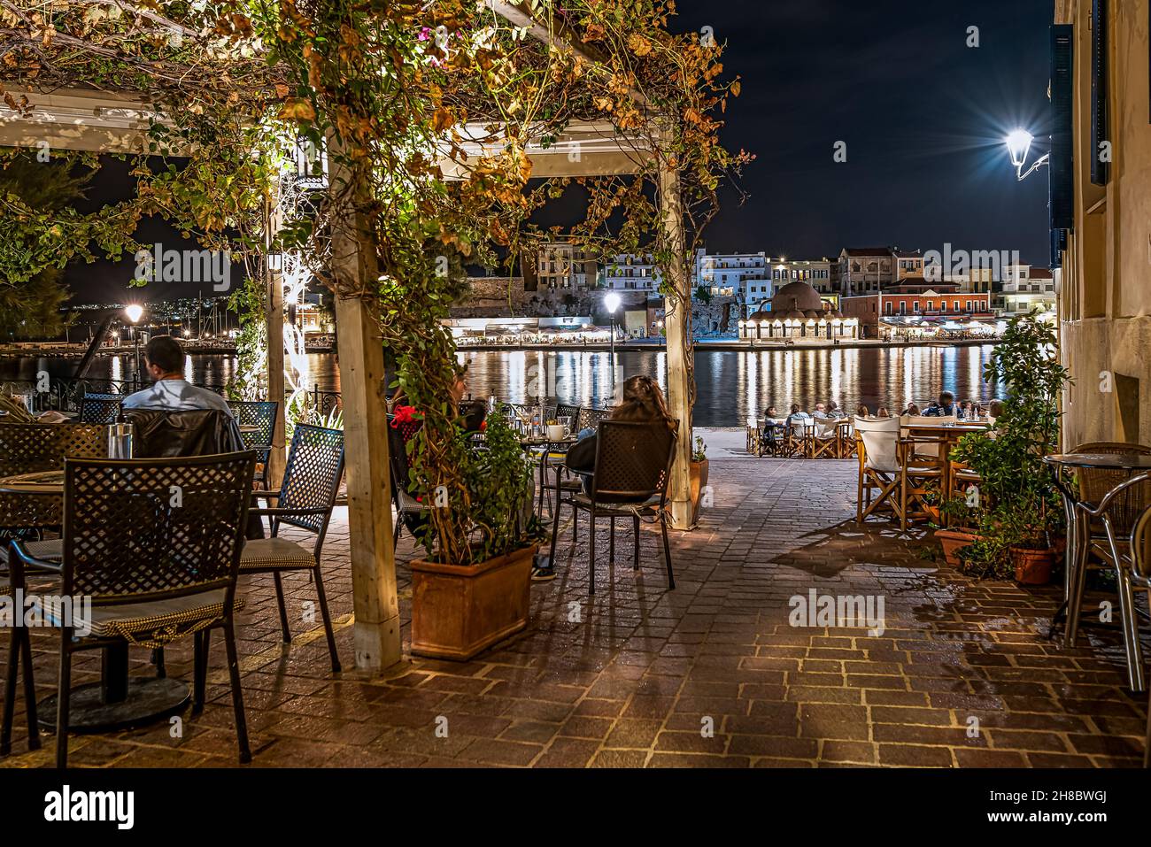 Un restaurant en plein air la nuit avec des clients assis dans une pergola, donnant sur le port de Chania, Crète, Grèce, 13 octobre 2021 Banque D'Images