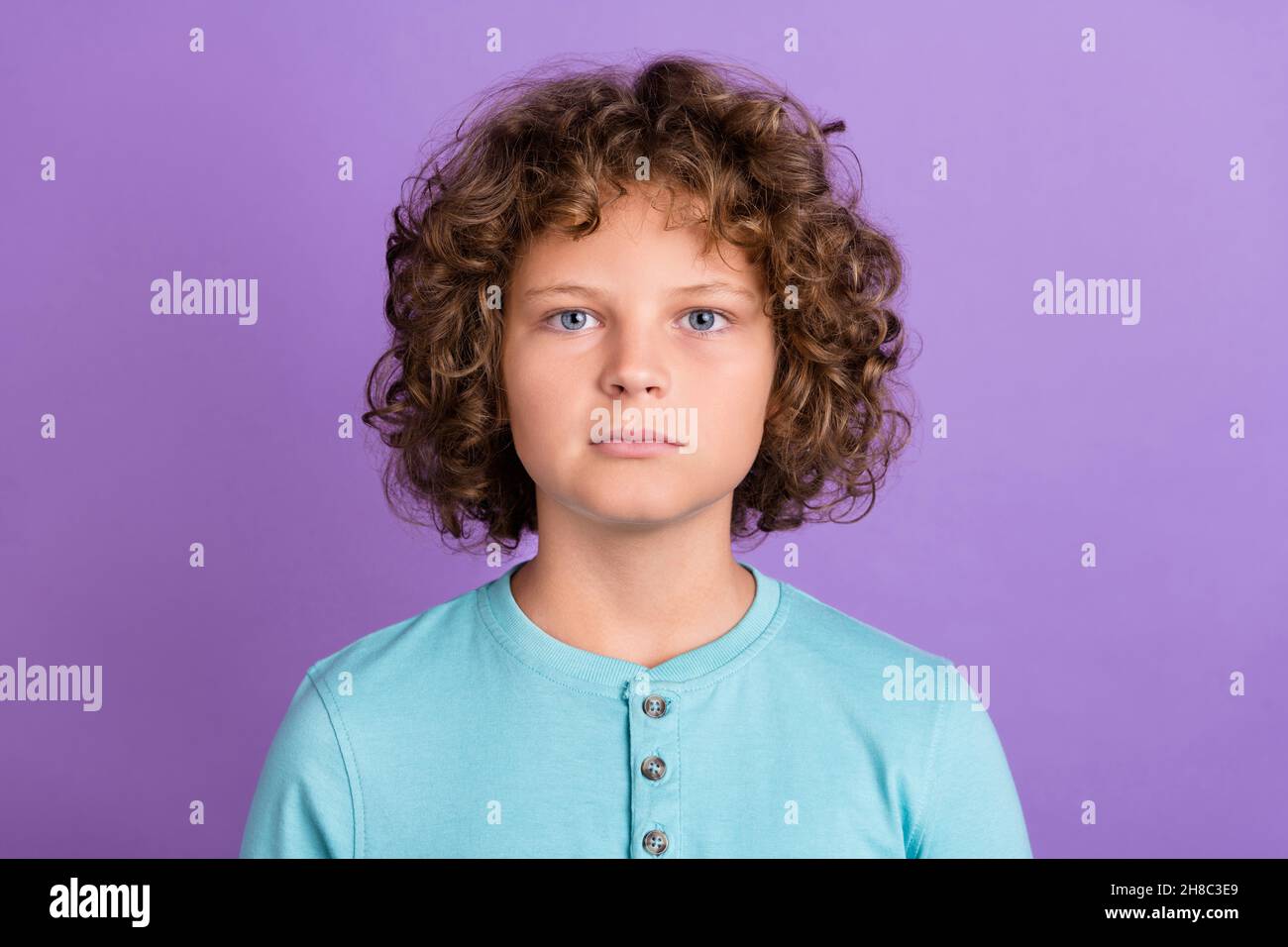 Portrait de contenu attrayant garçon à poils ondulés sérieux isolé sur fond violet vif de couleur violet Banque D'Images