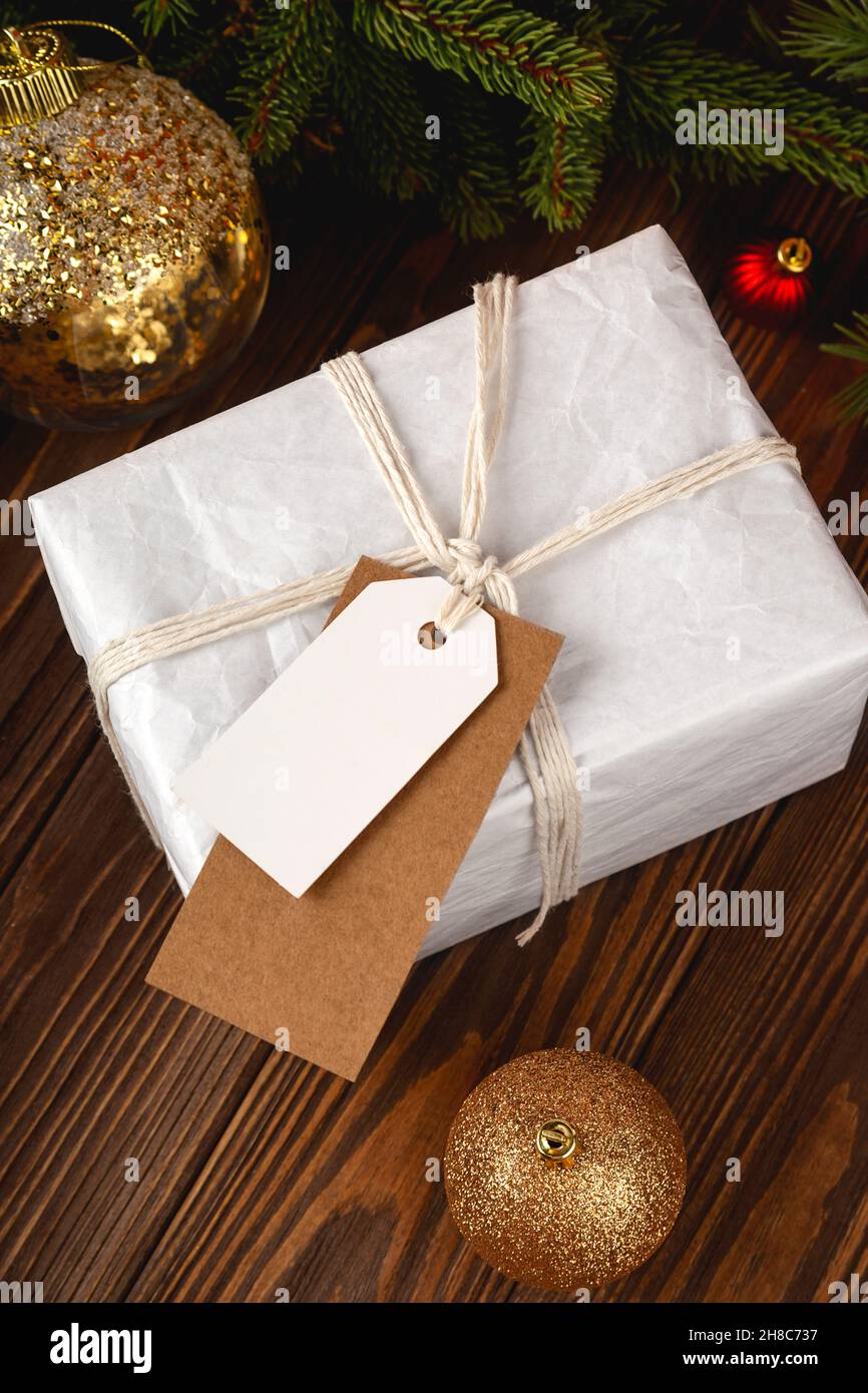 Maquette d'étiquette cadeau de Noël.Coffret cadeau blanc minimaliste sur table en bois avec décorations de fête. Banque D'Images