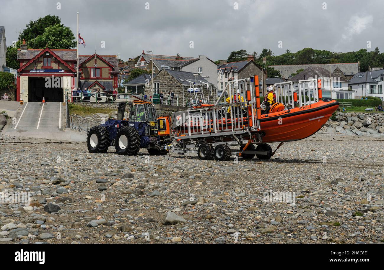 Tracteur et remorque semi-submersibles RNLI transportant le canot de sauvetage côtier Criccieth et montez la plage de poney vers la station du bateau de sauvetage. Banque D'Images