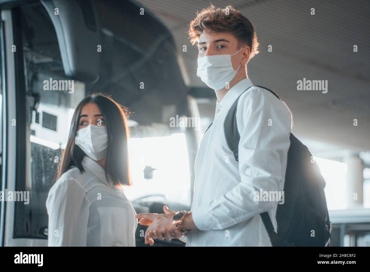 Jeunes garçons avec masque facial attendant que le bus se déplace vers leur destination Banque D'Images