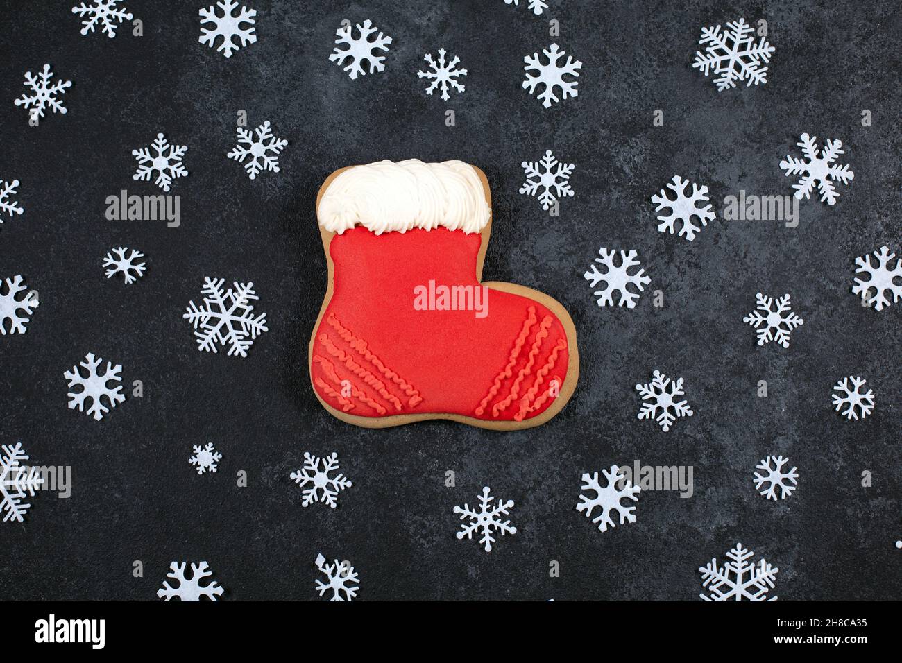 Délicieux biscuit au pain d'épice en forme de bottes et flocons de neige sur fond sombre.Stockage du nouvel an.Pâtisserie de fête.Bonbons traditionnels d'hiver.Flat lay, vue de dessus.Saison d'hiver Banque D'Images