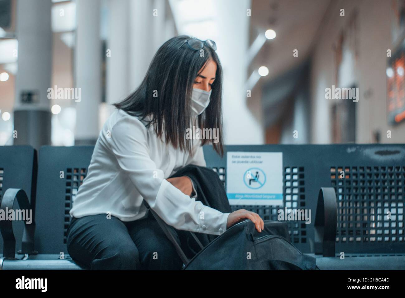 Jeune femme avec masque vérifiant ses bagages et la distance sociale Banque D'Images