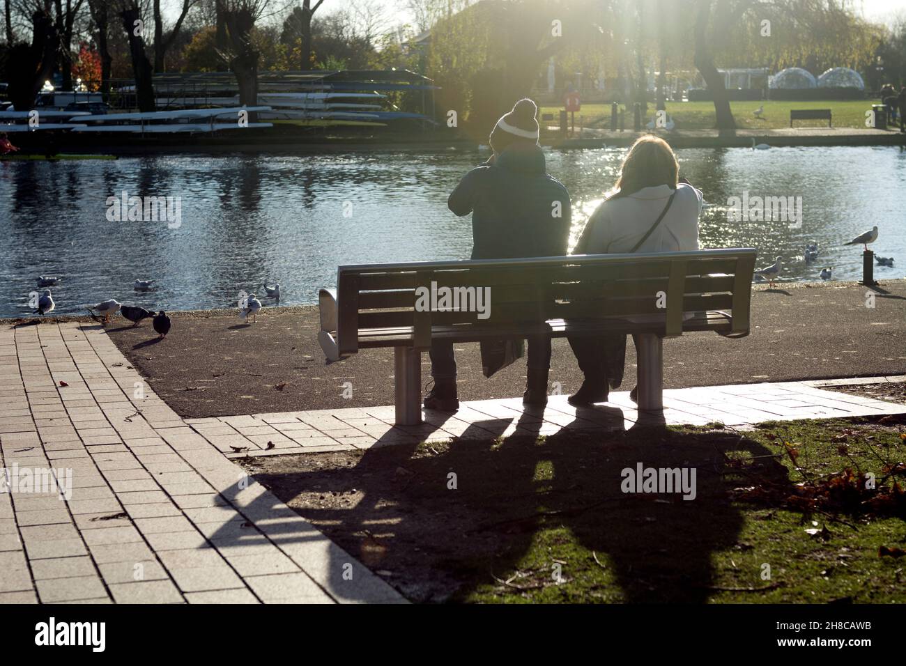 Deux personnes se sont assises sur un banc surplombant la rivière Avon au soleil de novembre, Stratford-upon-Avon, Warwickshire, Angleterre, Royaume-Uni Banque D'Images