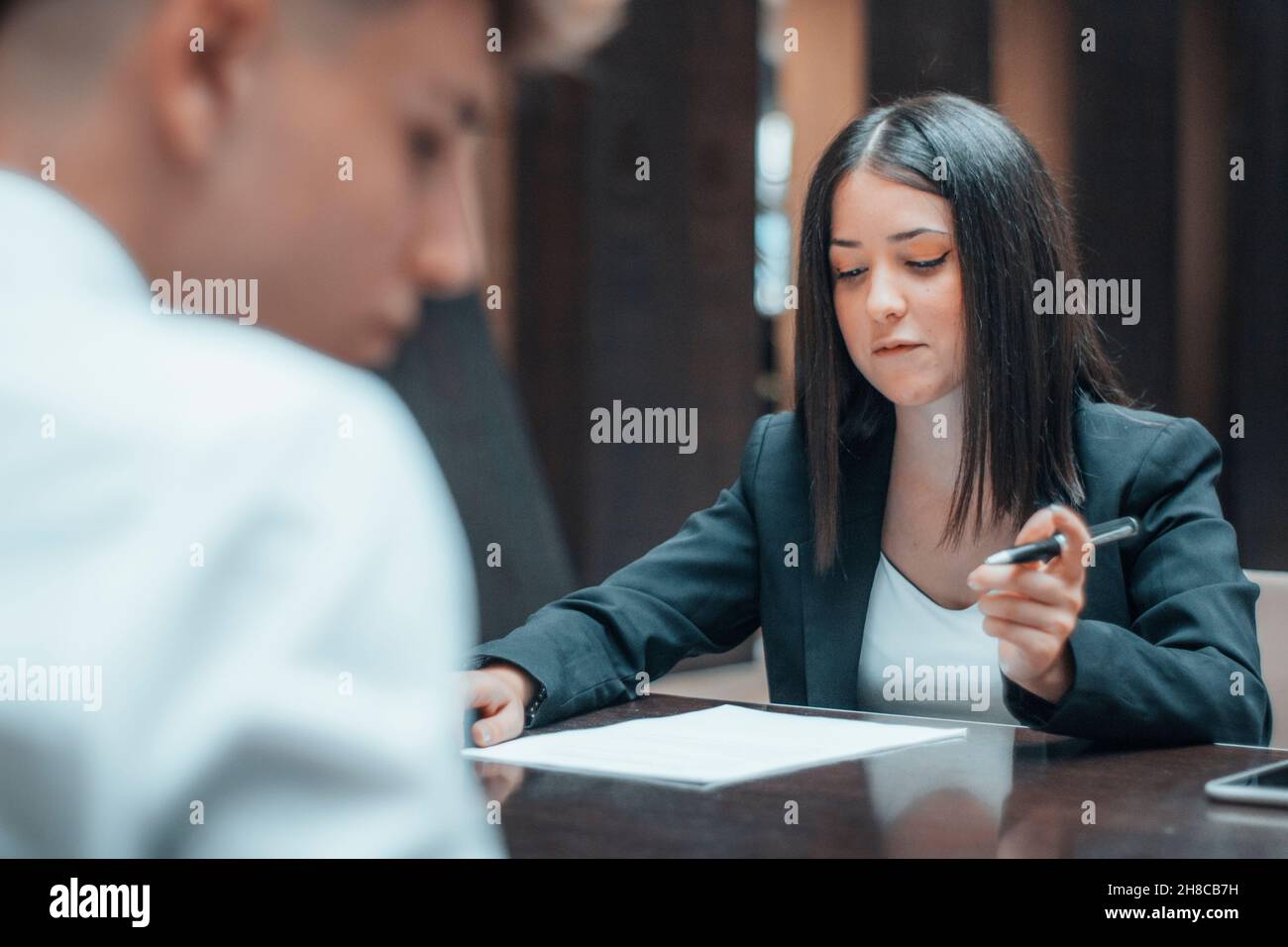 Femme gestionnaire analysant et étudiant les contrats et les rapports de son client à une table près de son bureau de travail Banque D'Images