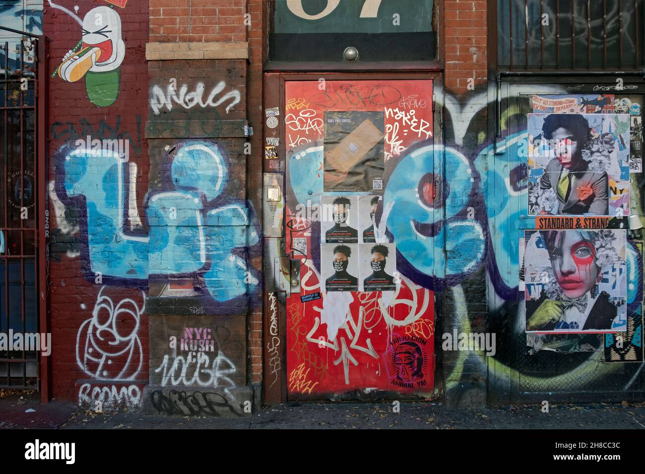 PAYSAGE URBAIN Une porte et un mur sur East Houston Street dans Lower Manhattan avec graffiti, art de rue, affiches et étiquettes. Banque D'Images