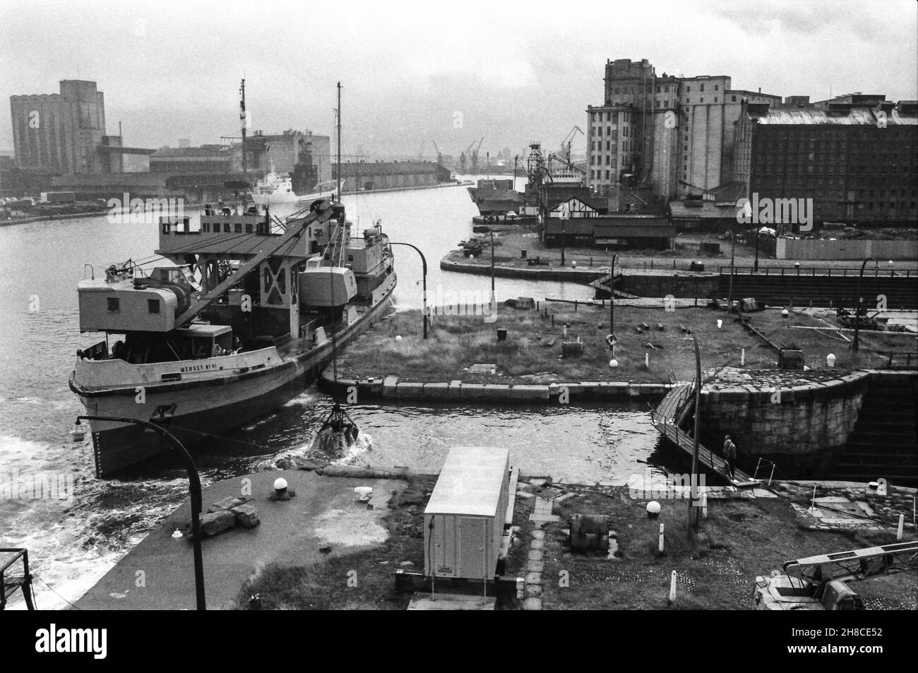 Birkenhead - deux quais secs dans West Float, d'un navire à l'entrée de la troisième.Le dredger 'Mersey No. 41' travaille à travers les entrées à l'aide d'une pince sur une grue.Les portes de verrouillage sont fermées sur les deux quais secs, qui ont été remplis depuis.Photo prise en février 1984. Banque D'Images