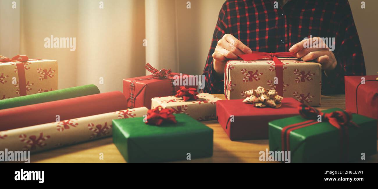femme emballant des cadeaux à la maison. nouez un noeud Banque D'Images
