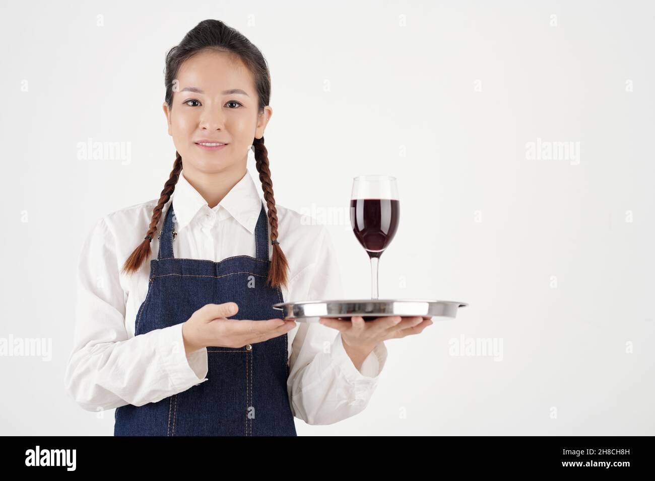 Serveuse de restaurant positive servant un verre de bon vin rouge au client, isolée sur blanc Banque D'Images