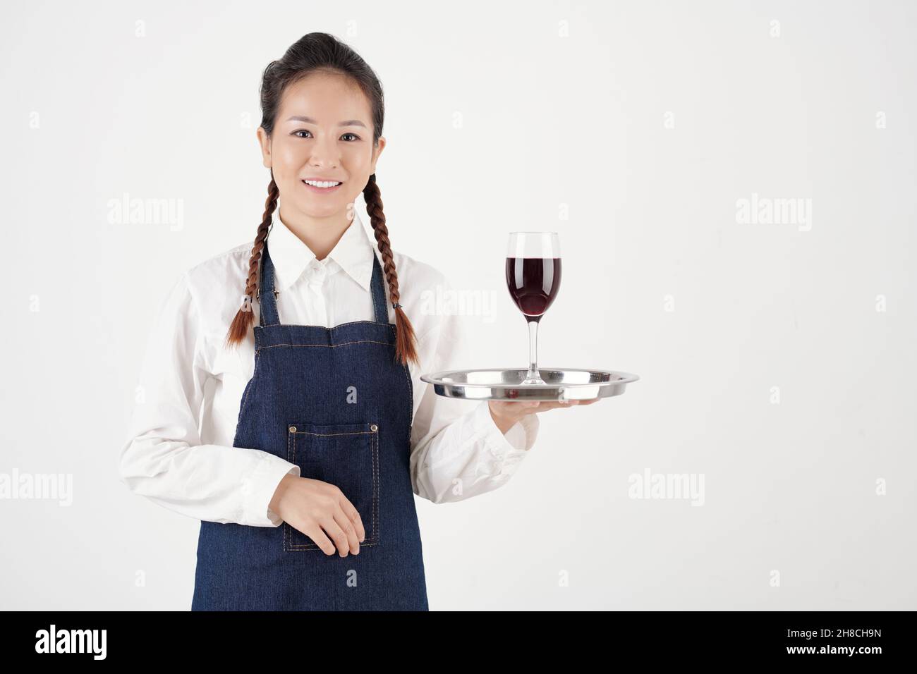 Portrait d'une serveuse souriante tenant un verre de vin sur un plateau métallique Banque D'Images