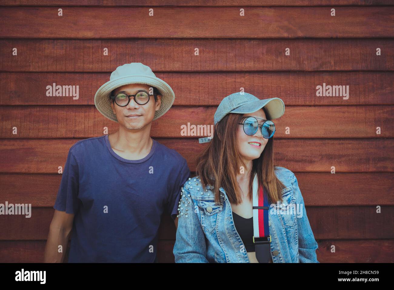 couples asiatiques portant des vêtements chapeau et style de vie décontracté debout contre un mur en bois Banque D'Images