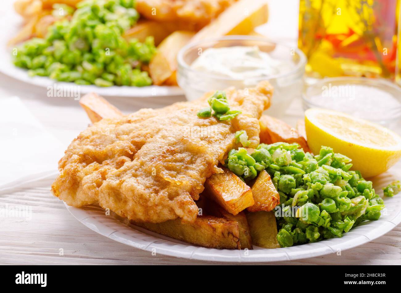 L'alimentation de rue britannique traditionnel poisson et frites avec sauce tartare et petits pois sur plaques de papier Banque D'Images