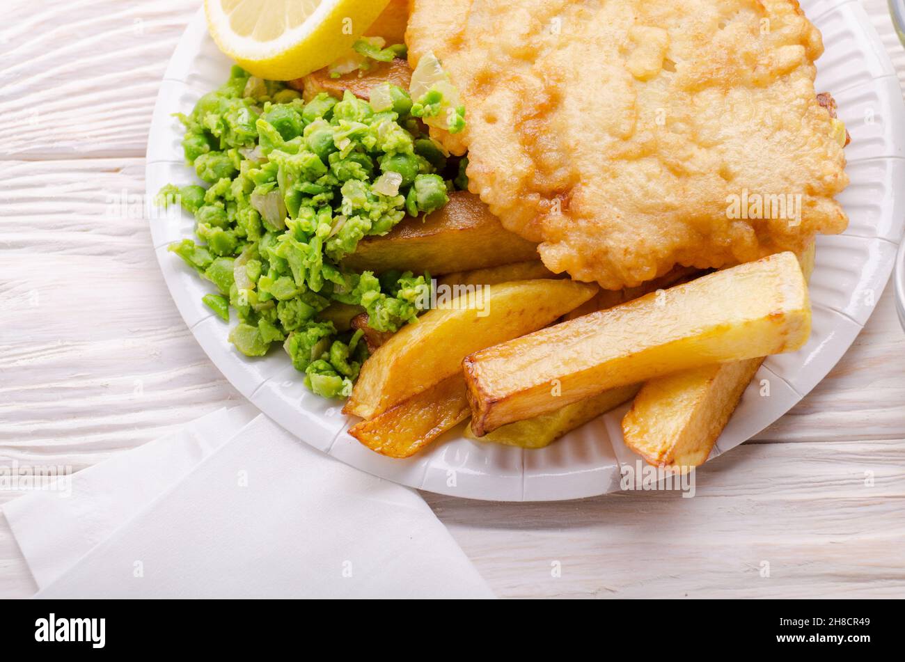 L'alimentation de rue britannique traditionnel fish and chips avec petits pois sur plaques de papier Banque D'Images