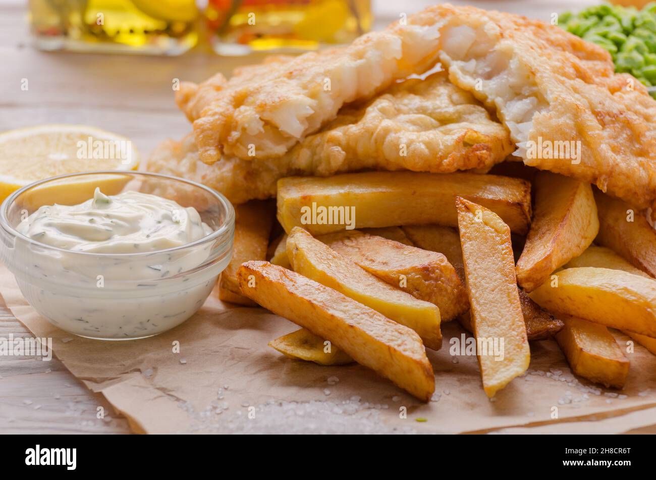 L'alimentation de rue britannique traditionnel poisson et frites avec sauce tartare et citron sur papier boulangerie Banque D'Images