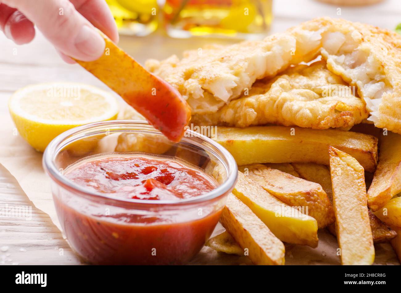 L'alimentation de rue britannique traditionnel poisson et frites avec sauce ketchup et citron sur papier boulangerie Banque D'Images