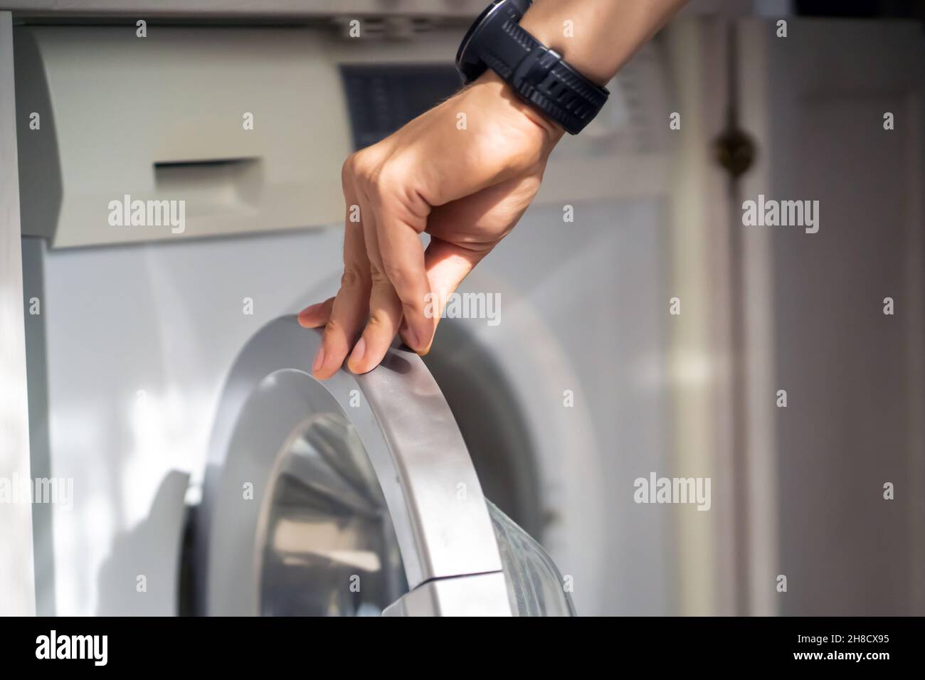 L'homme utilise la machine à laver moderne. Banque D'Images