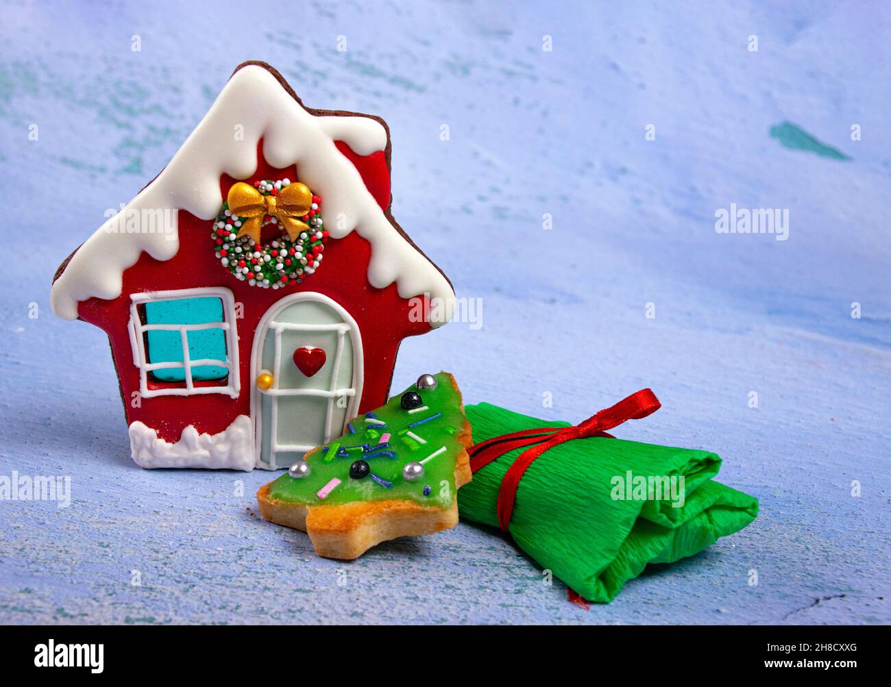 La scène du nouvel an, des biscuits en forme de maison et un arbre de Noël et un cadeau enveloppé sur un fond clair, comme la neige. Banque D'Images