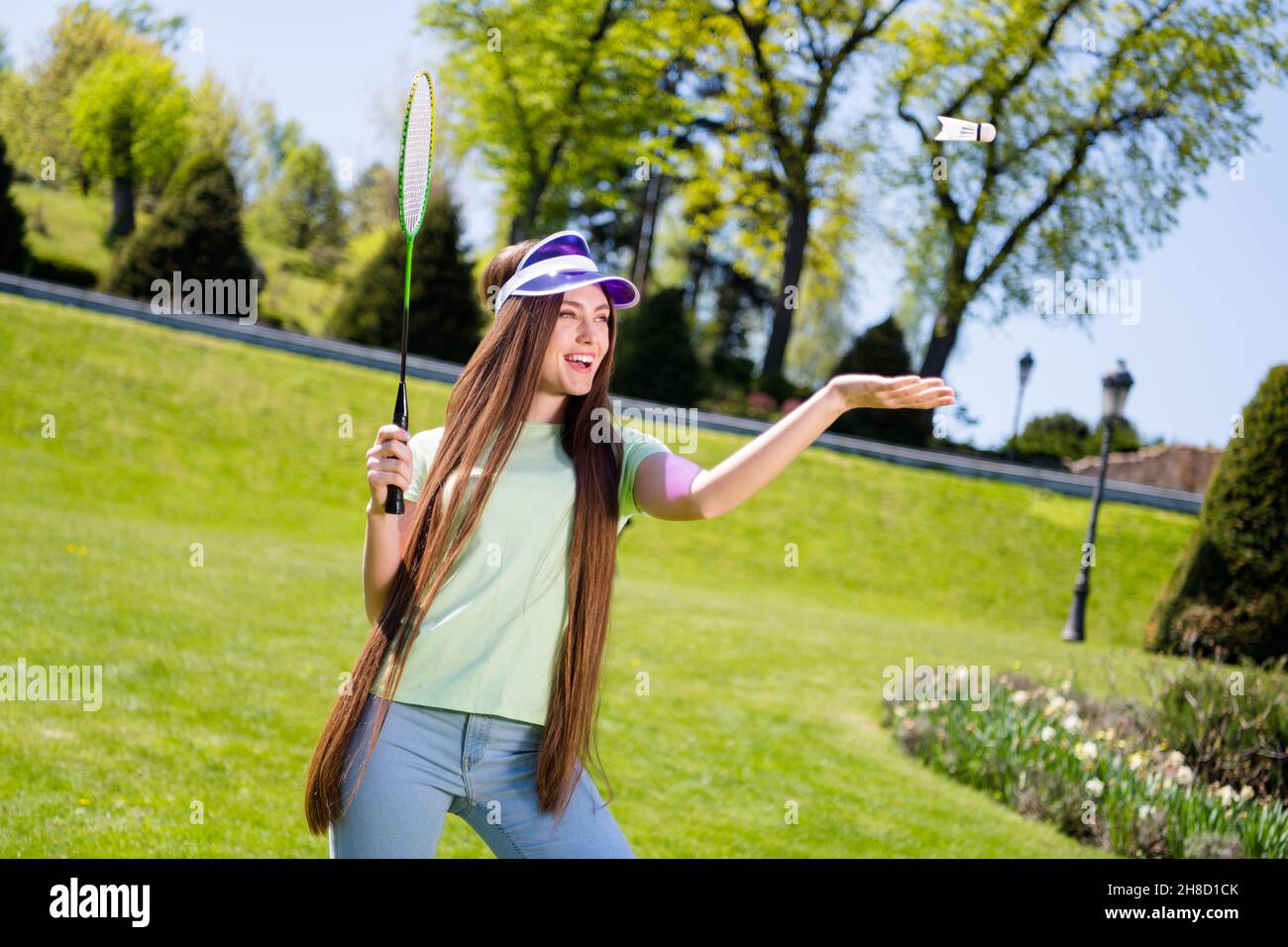 Photo de jeune femme joyeuse sourire heureux positif jouer au jeu de badminton sportive Fly air raquetet en plein air Banque D'Images