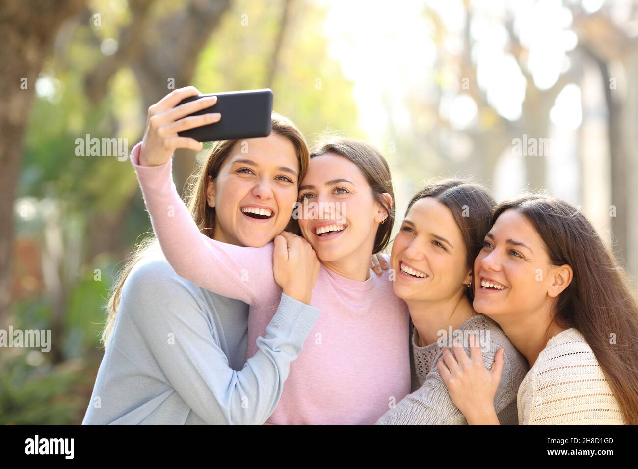 Quatre amis heureux prenant des selfies avec un smartphone dans la rue Banque D'Images