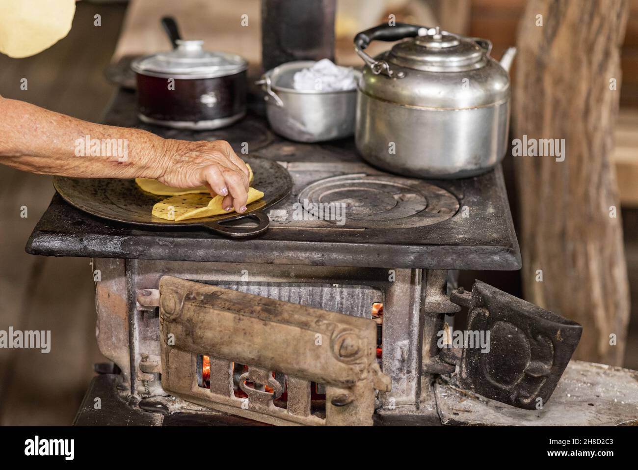 Vieille femme qui cuisine des tortillas de maïs typiques du Costa Rica dans une maison en bois à Tilaran, Guanacaste Banque D'Images