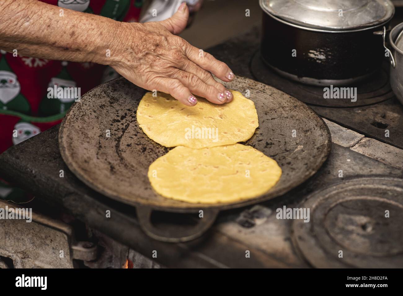 Vieille femme qui cuisine des tortillas de maïs typiques du Costa Rica dans une maison en bois à Tilaran, Guanacaste Banque D'Images