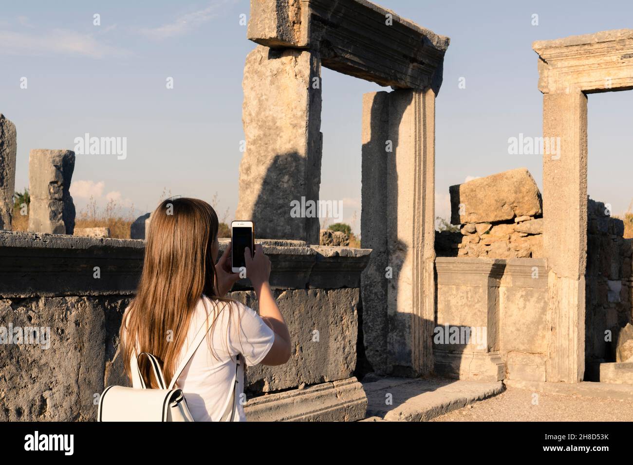 Une touriste féminine prend des photos sur son téléphone des ruines grecques anciennes, le site historique de Perge ou Aspendos, le tourisme à Belek ou Antalya en t. Banque D'Images