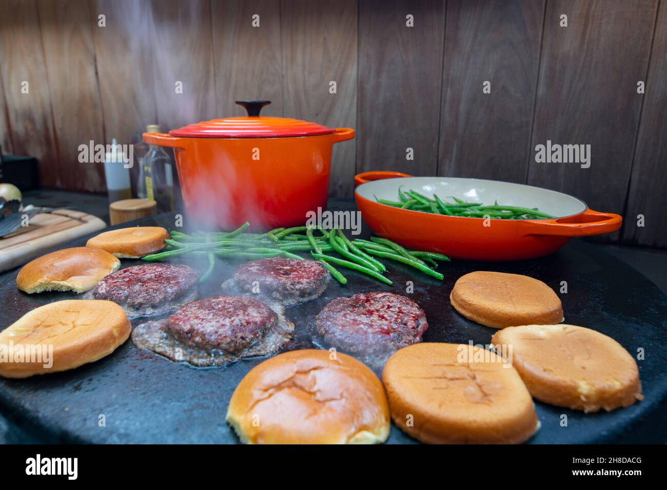 Aliments hamburgers cuisant sur un gril plat à l'extérieur dans une cuisine de patio maison Banque D'Images