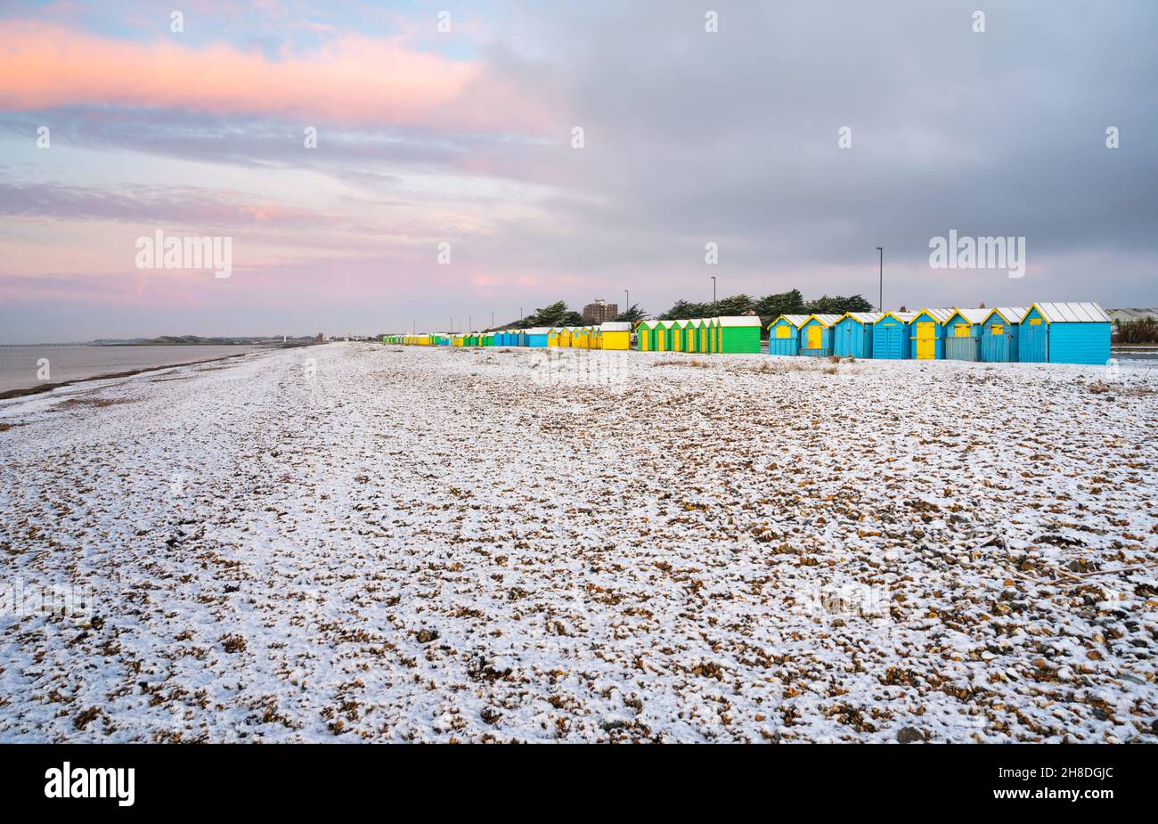 Des cabanes de plage et la plage couverte d'une fine couche de neige en hiver à Littlehampton, West Sussex, Angleterre, Royaume-Uni. Banque D'Images