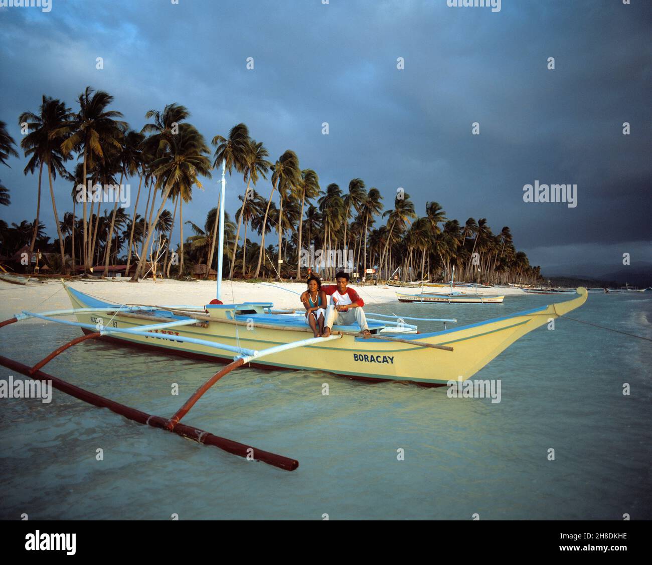 Philippines.Île Boracay.Jeune couple local à la plage assis sur un canoë-kayak. Banque D'Images