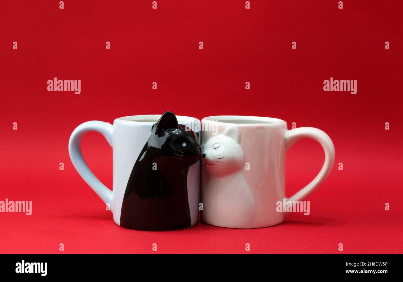 Mugs sous forme de chats amoureux sur fond rouge.Carte postale concept Saint Valentin, bannière.Copier l'espace Banque D'Images