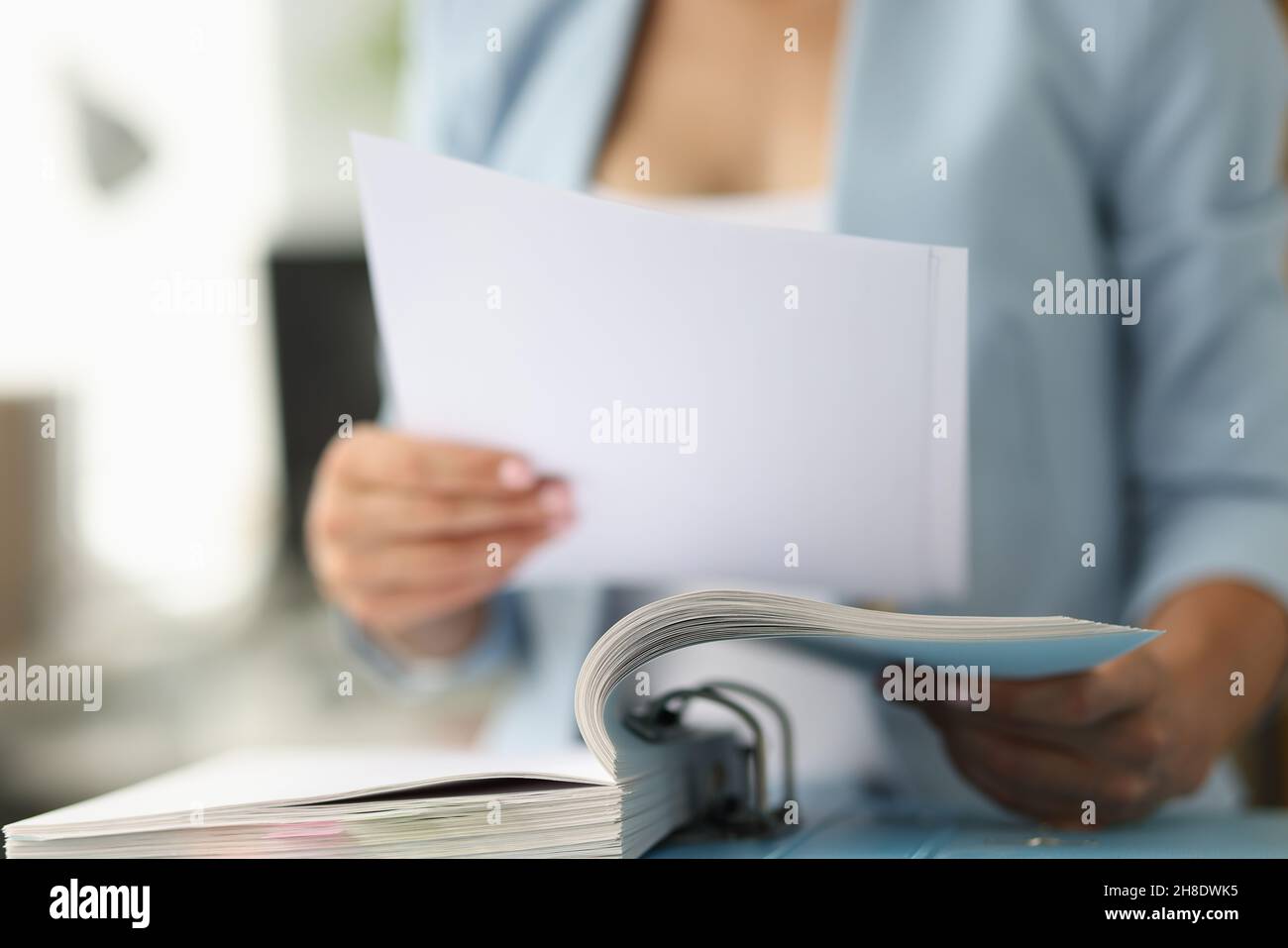 Femme d'affaires en costume regardant des documents de la fermeture de dossier Banque D'Images