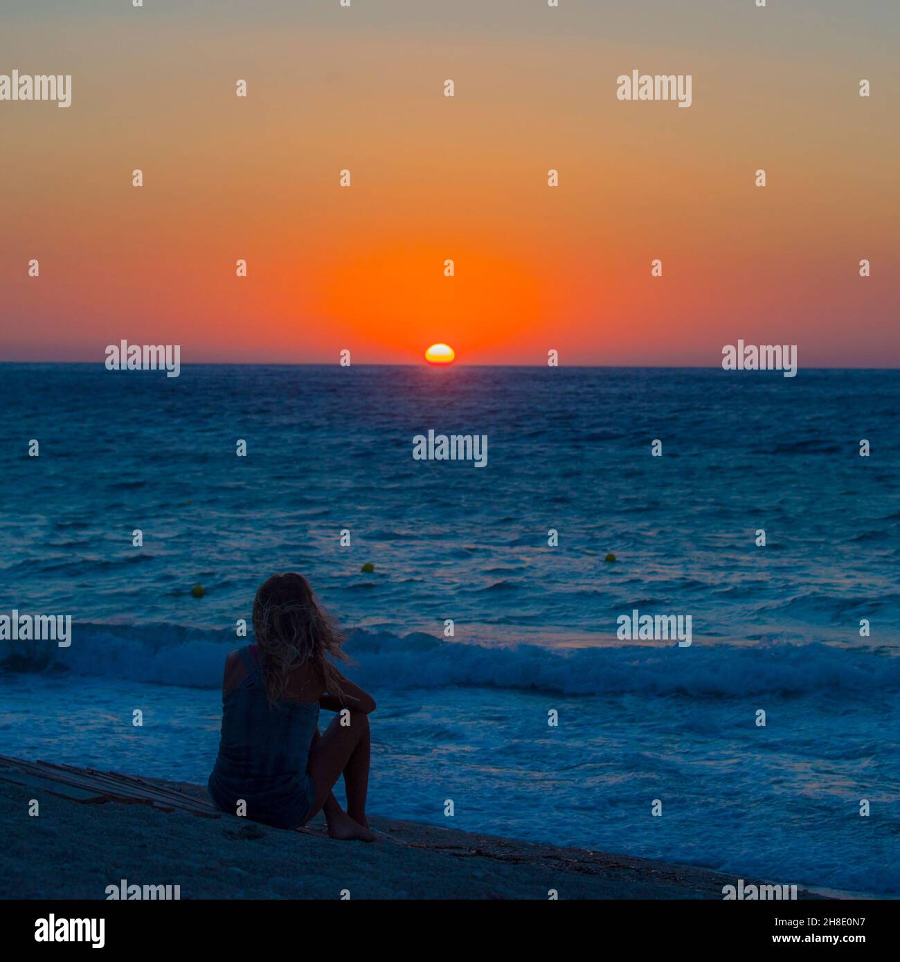 Lefkada Grèce coucher de soleil observé par une femme silhouettée debout dans les eaux Banque D'Images
