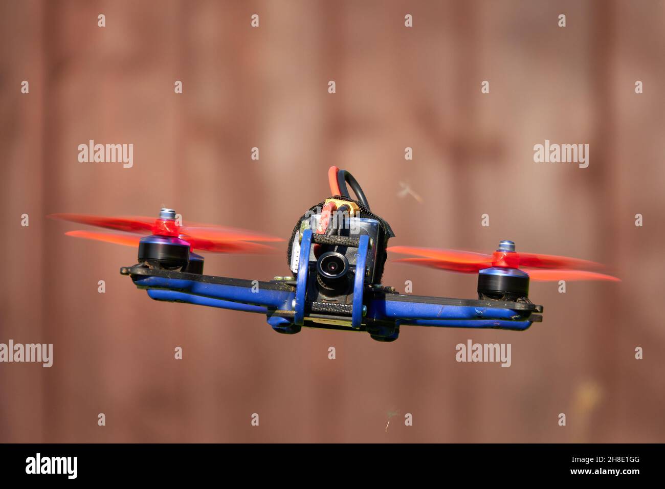 Le drone noir fait également la course de quad, avec hélice orange, se hante devant le mur brun de bois.Allemagne. Banque D'Images