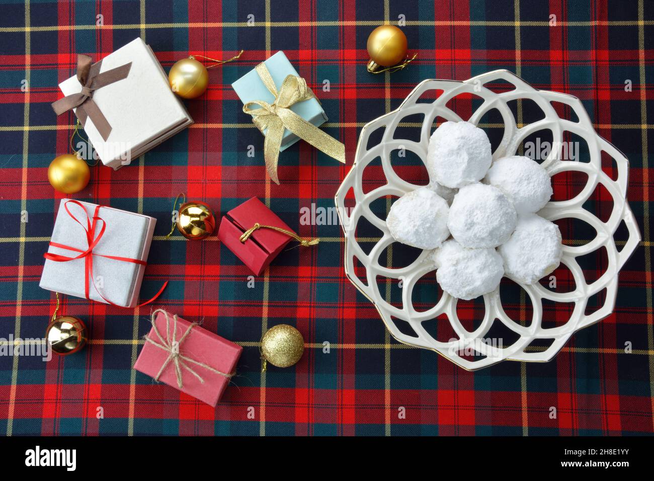 Kourabiedes, sucreries de noël grecques, cadeaux et boules de noël sur un tissu écossais bleu rouge Banque D'Images
