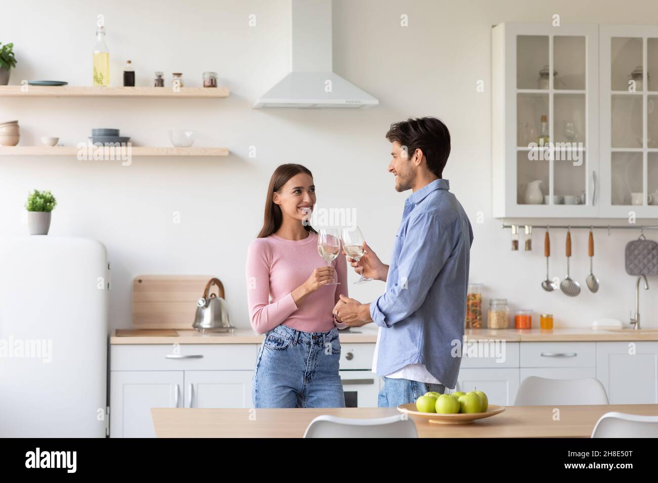 Joyeux jeune femme européenne et gars clink verres, appréciant le moment tendre dans la cuisine Banque D'Images