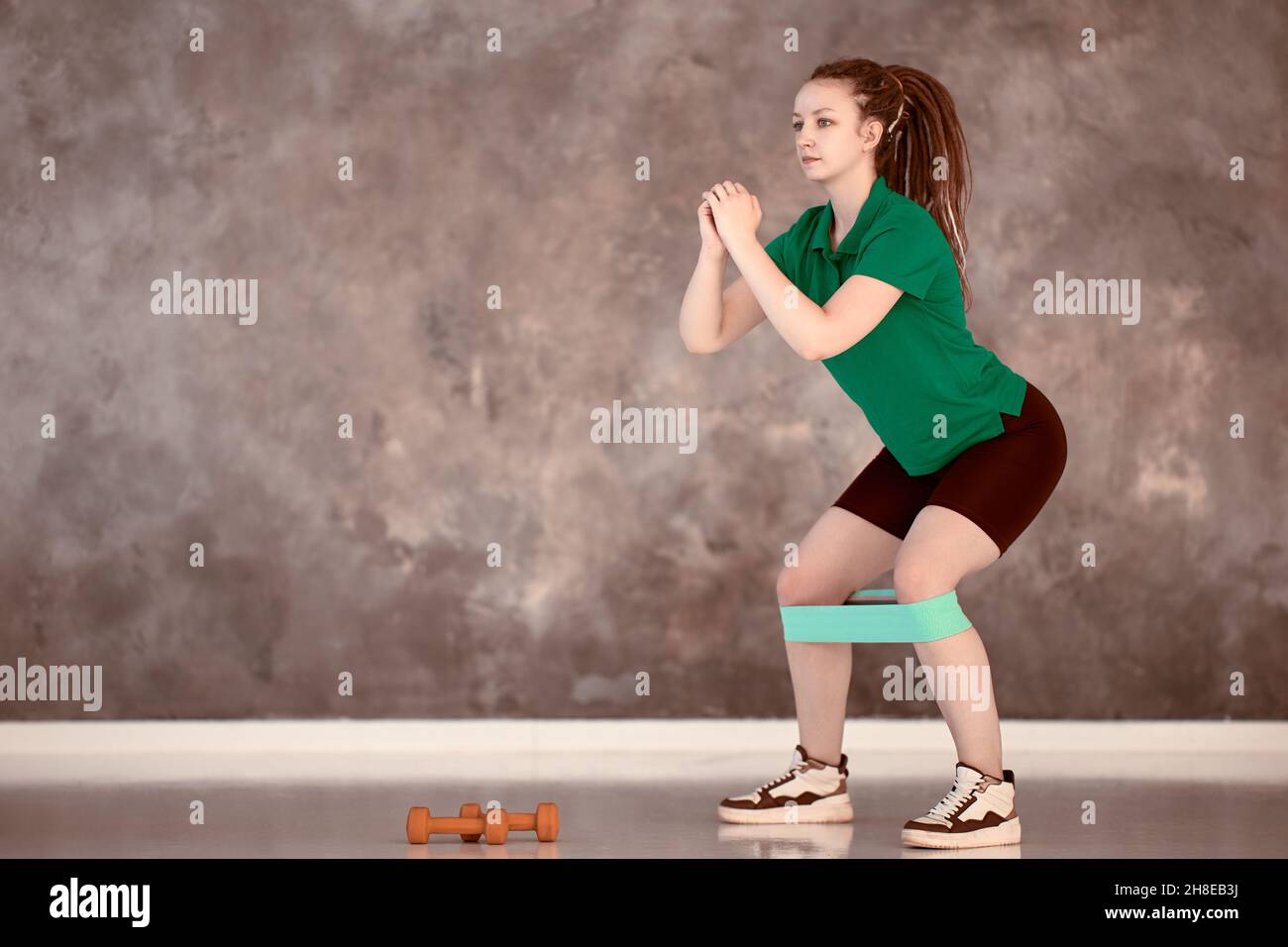 Bracelet élastique sportif pour l'entraînement sur les jambes d'une femme caucasienne sérieuse en salle de sport. Banque D'Images