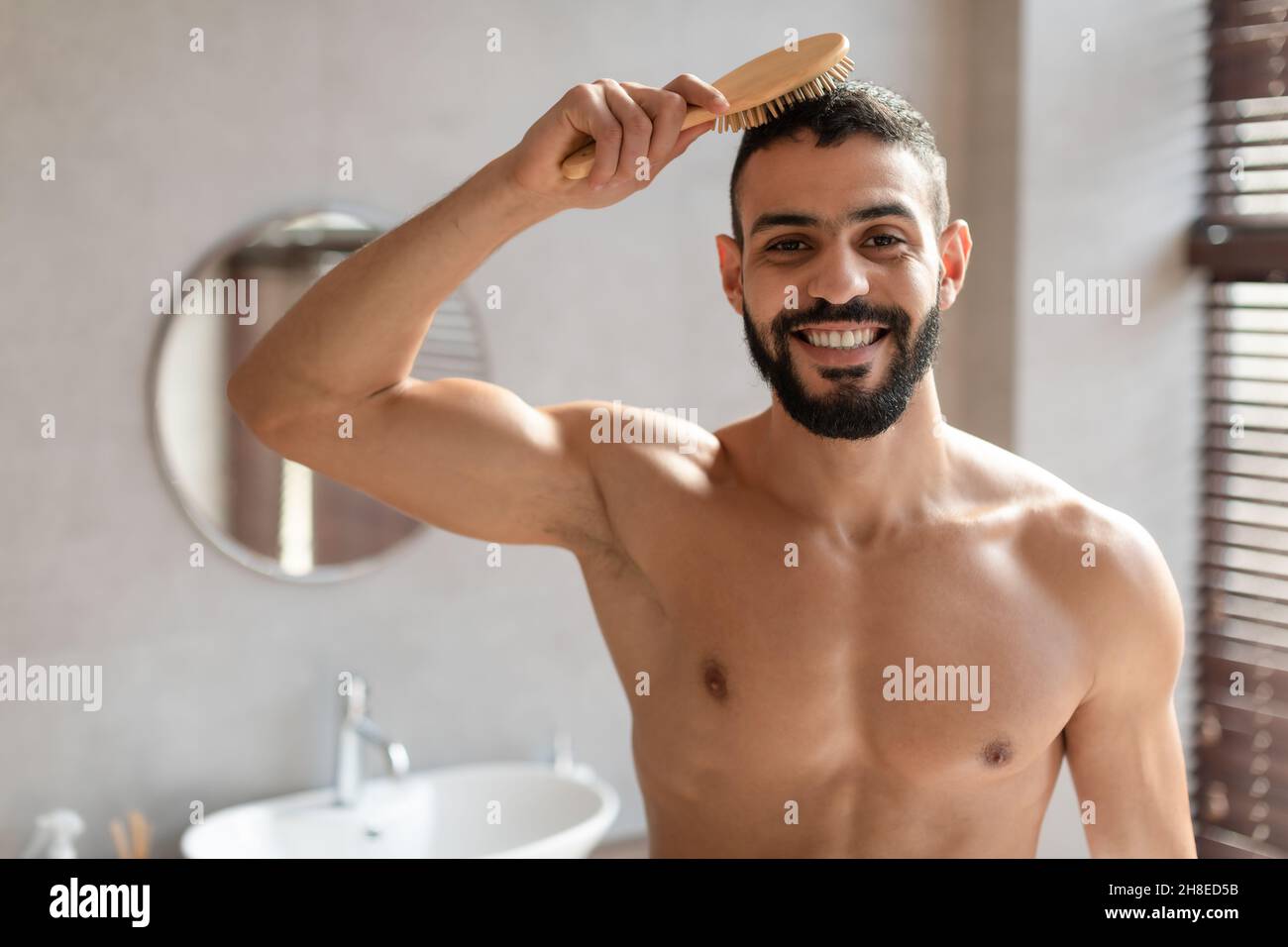 Portrait d'un jeune homme se brossant les cheveux en regardant l'appareil photo Banque D'Images