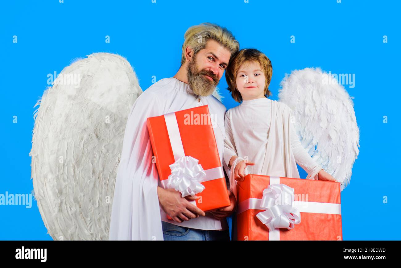 Père et fils heureux en costume d'ange avec cadeau.Anges de Saint-Valentin avec ailes blanches et boîte cadeau Banque D'Images