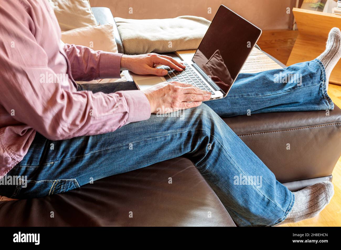 Vue latérale de crop homme d'affaires anonyme assis sur un canapé et dactylographiant sur un ordinateur portable tout en travaillant à la maison Banque D'Images