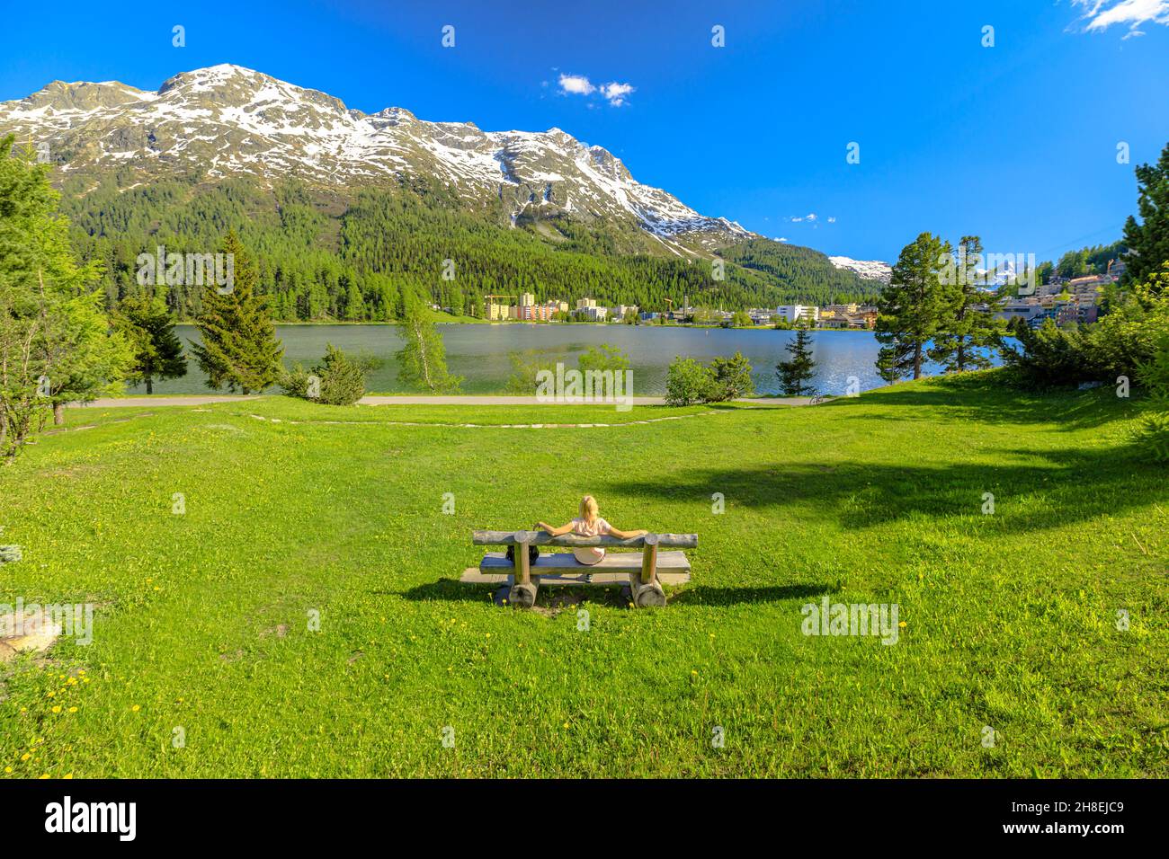 Voyageur femme assise sur un banc de parc de Saint-Moritz près du lac Saint-Moritz en Suisse.Le lac de Saint-Moritz dans le canton des Grisons, dans la région de Maloja. Banque D'Images