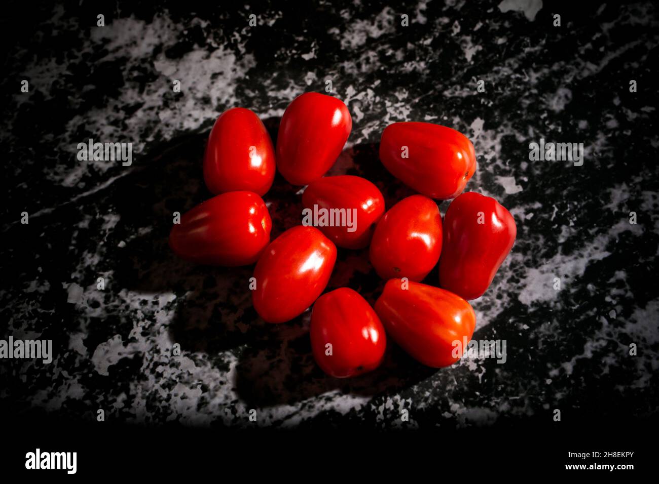 Tomates prune sur fond noir.Concept d'alimentation saine. Banque D'Images