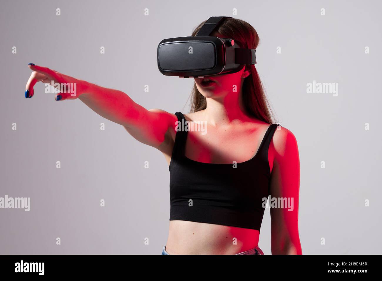 Bonne jeune femme jouant sur des lunettes VR.Concept de réalité virtuelle avec la jeune fille s'amusant dans les lunettes de réalité virtuelle.Métaverse. Banque D'Images