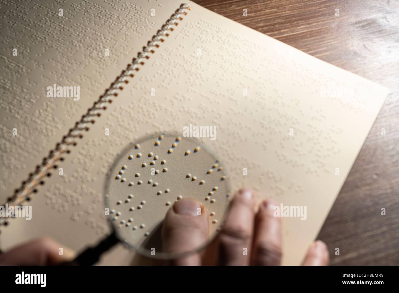 Le foyer d'une loupe sur une page écrite en braille, le système de lecture tactile en relief pour les aveugles Banque D'Images