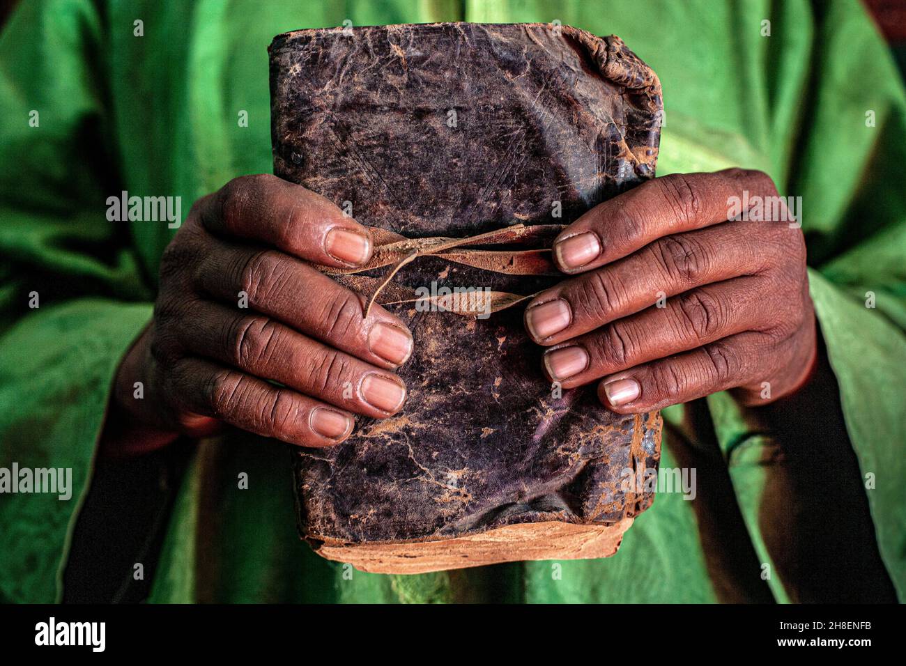 Des mains de sexe masculin tenant un livre manuscrit lié en cuir à la bibliothèque privée Al-Wangari, à Tombouctou , Mali , Afrique . Banque D'Images