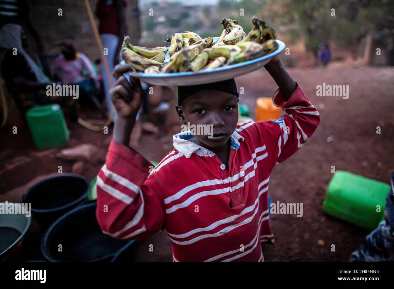 Garçon et fille portent des bananes sur sa tête au marché.Un jeune homme vend des bananes à la campagne , au Mali , en Afrique de l'Ouest Banque D'Images